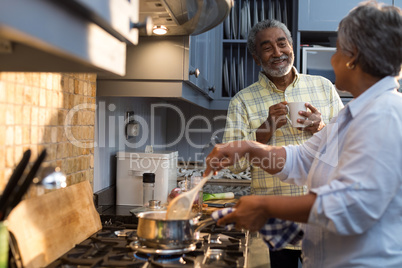 Smiling man coffee cup talking with woman preparing food