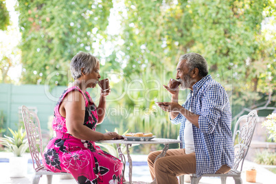 Side view of couple drinking coffee in yard