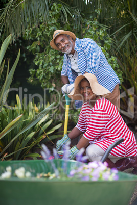 Portrait of senior couple gardening in yard