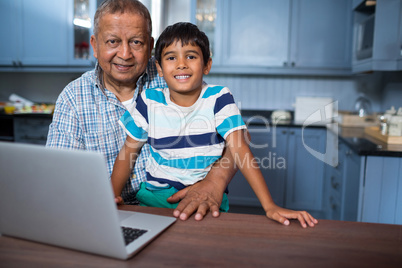 Portrait of grandfather with boy using laptop