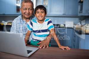 Portrait of grandfather with boy using laptop