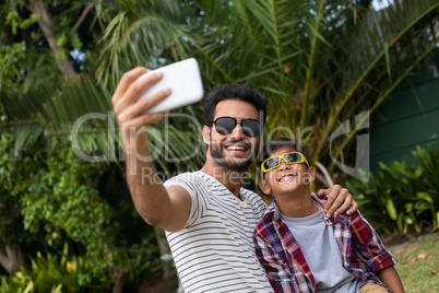 Father and son wearing sunglasses while taking selfie