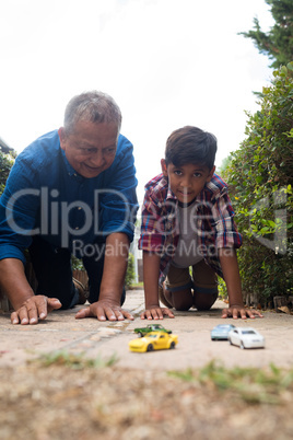 Boy and grandfather playing with toy cars against sky