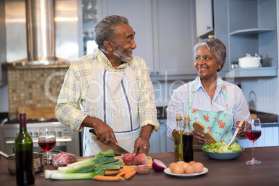 Smiling couple talking while preparing food at home