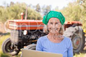 Portrait of happy woman using laptop in olive farm