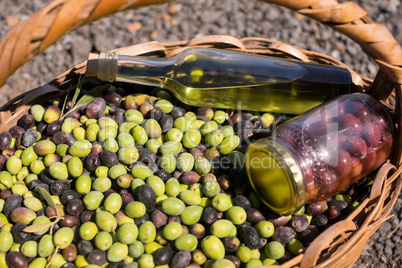 Close-up of olives, jar and olive oil bottle in basket