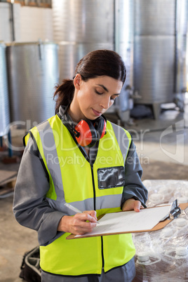 Female technician writing in clipboard