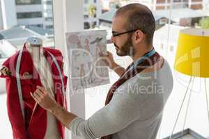 Designer examining clothing on mannequin