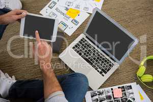 Cropped image of designer using digital tablet while sitting on floor