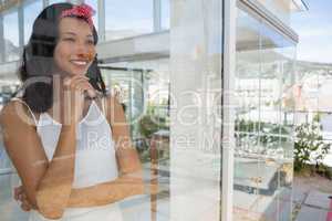 Smiling thoughtful businesswoman seen through glass
