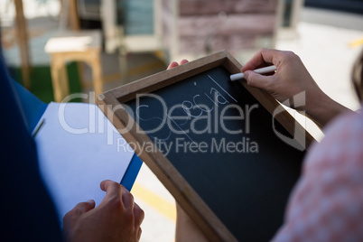 Woman writing menu while coworker holding file