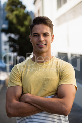 Handsome young man with arms crossed standing in city