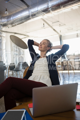 Businesswoman with hands behind head relaxing at office