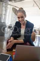 Thoughtful smiling businesswoman looking down while sitting on chair