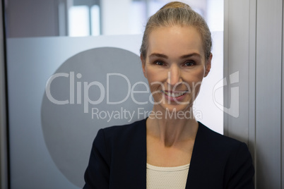 Portrait of smiling businesswoman standing by door