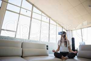 Businesswoman mediating while using virtual reality on sofa in office