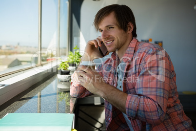 Businessman talking on phone while having coffee