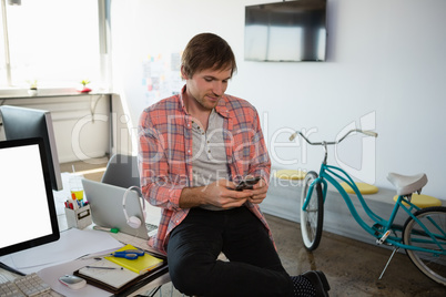 Businessman using phone while sitting on desk