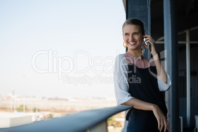 Smiling businesswoman talking on phone in balcony