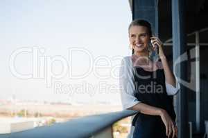 Smiling businesswoman talking on phone in balcony
