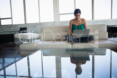 Young woman using laptop while sitting on sofa at office