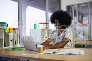 Smiling man using laptop at office