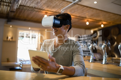 Man using virtual reality headset and digital tablet in restaurant