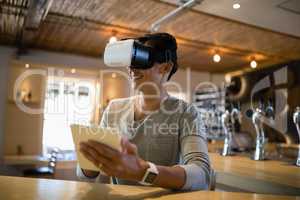 Man using virtual reality headset and digital tablet in restaurant