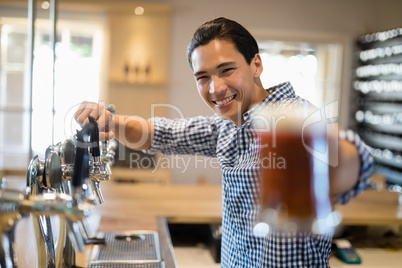 Bar tender offering glass of beer to customer