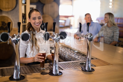 Portrait of female bartender holding glass of beer