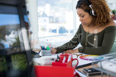 Female executive in headphones working at desk