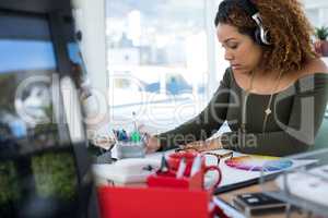 Female executive in headphones working at desk