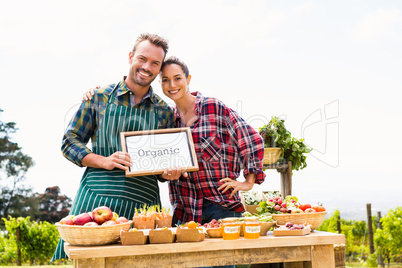 Portrait of couple with blank blackboard selling organic vegetables