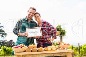 Portrait of couple with blank blackboard selling organic vegetables