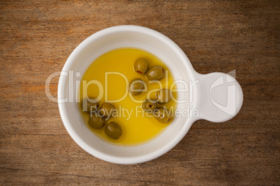 Overhead view of green olive with oil in container