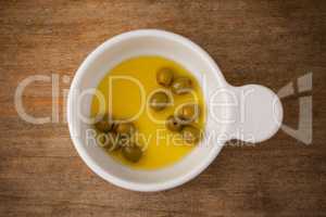 Overhead view of green olive with oil in container