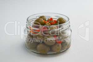 Green olives and herbs in glass jar