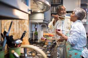 Man feeding woman while standing in kitchen