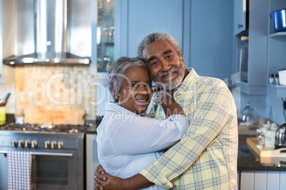 Portrait of couple embracing while standing in kitchen