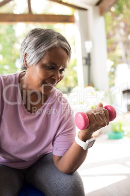 Close up of smiling senior woman exercising with dumbbell