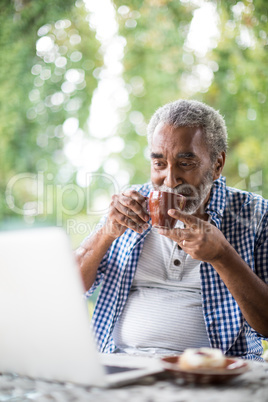 Man having drink while using laptop