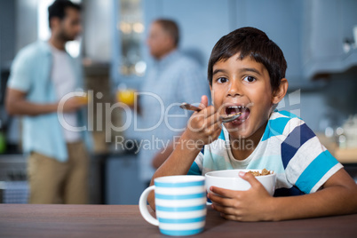 Portrait of boy having breakfast with family in background