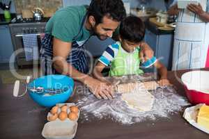 High angle view father assisting son for rolling dough