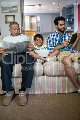 Boy with father and grandfather sitting on sofa