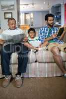 Boy with father and grandfather sitting on sofa