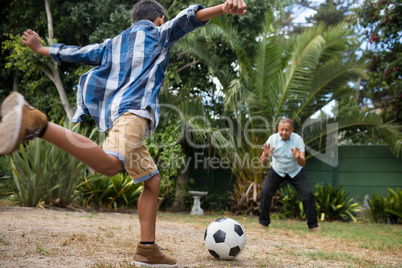 Boy playing soccer with grandfather