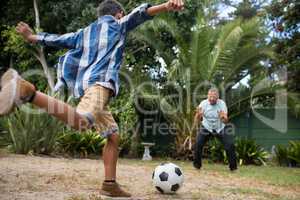 Boy playing soccer with grandfather