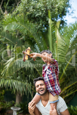 Happy father carrying son while standing in yard