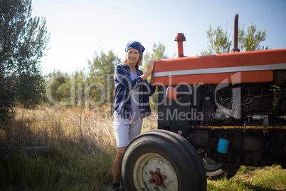 Portrait of confident woman standing near tractor in olive farm