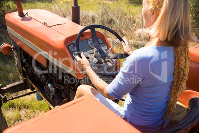 Rear view of woman driving tractor in olive farm